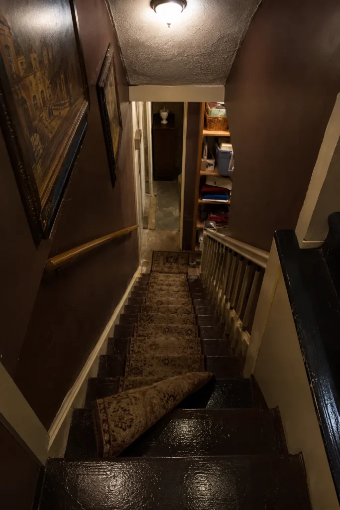 Safe basement staircase avoiding common mistakes with non-slip treads, warm lighting, secure railing, flat wall decor, hidden storage, and clear steps.