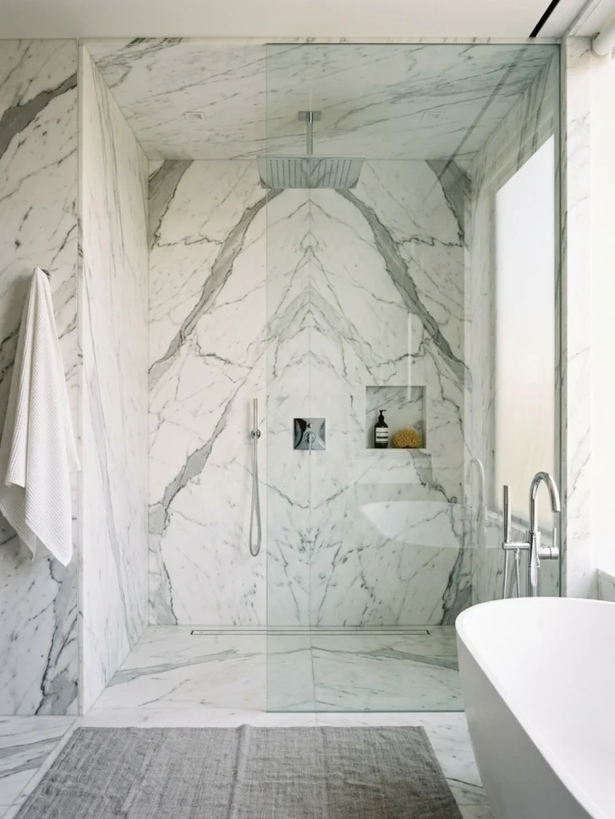 Marble shower with clear glass enclosure and rainfall showerhead