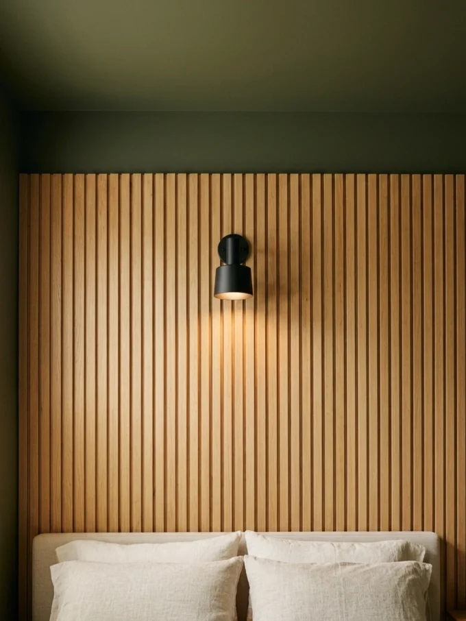 A wooden slatted headboard with a black wall light and white pillows