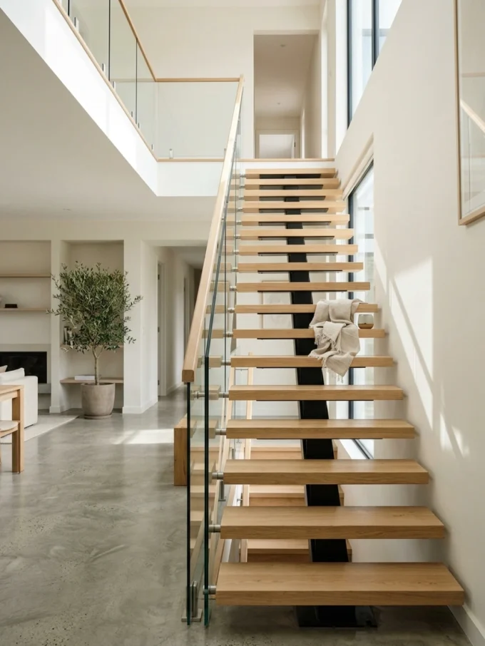 A modern open-riser staircase with wooden steps and glass railing
